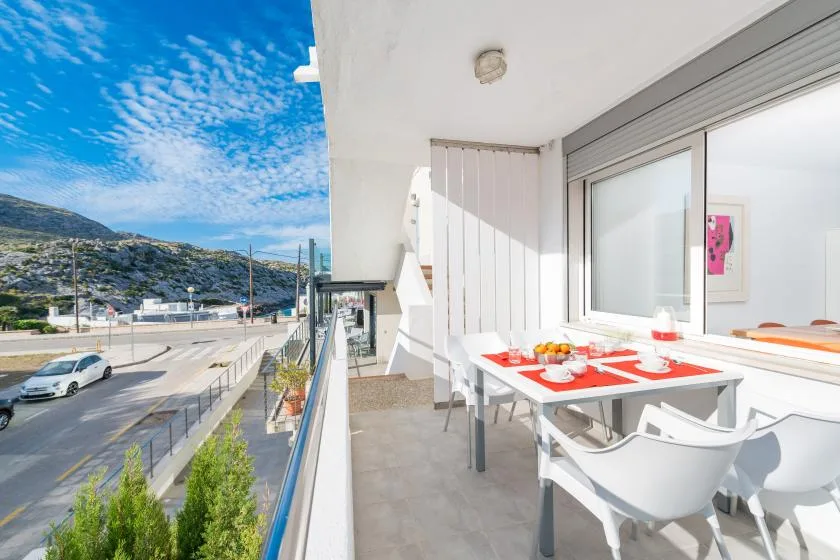 Comedor en un balcón con una mesa junto a grandes ventanas y vistas a la calle y las colinas.
