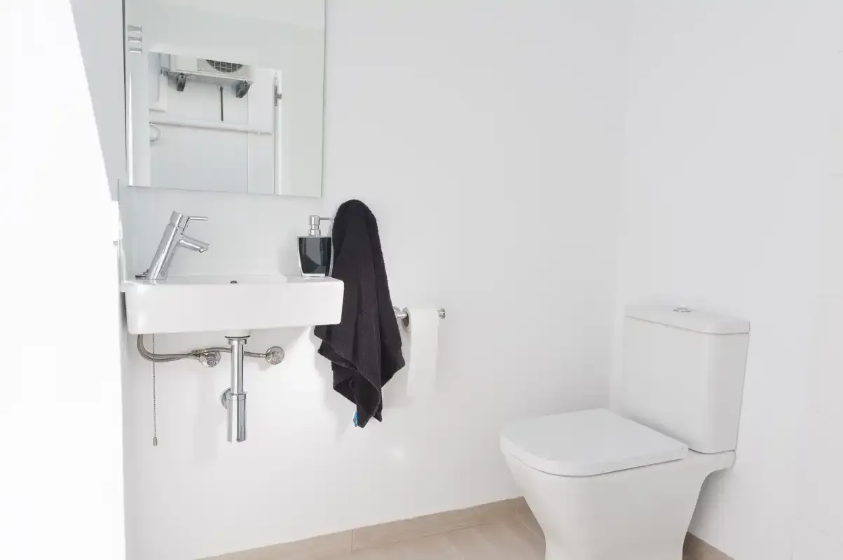 Un baño luminoso con un lavabo suspendido y un inodoro.