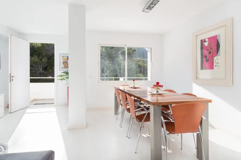 Un comedor luminoso con una mesa larga y asientos junto a una ventana grande.