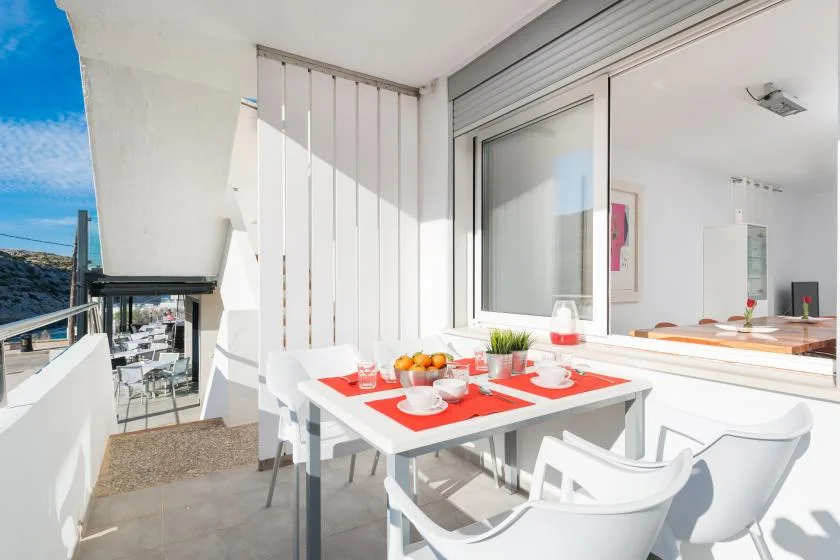 Una luminosa zona de comedor al aire libre con una mesa junto a grandes ventanas.