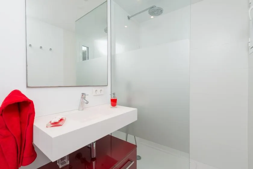 Un baño luminoso con lavabo suspendido y ducha de cristal.