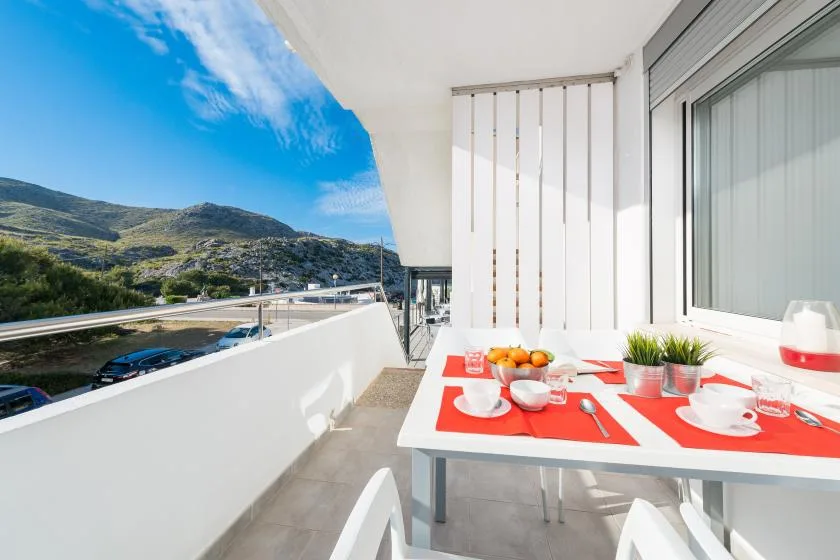 Una zona de comedor en un balcón con la mesa puesta y vistas a las montañas.