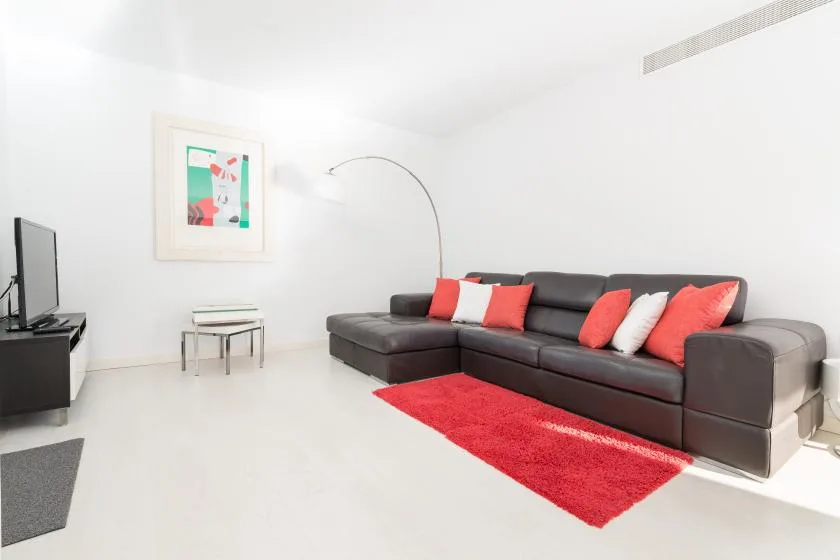 Una sala luminosa con asientos oscuros, una alfombra roja y arte enmarcado.