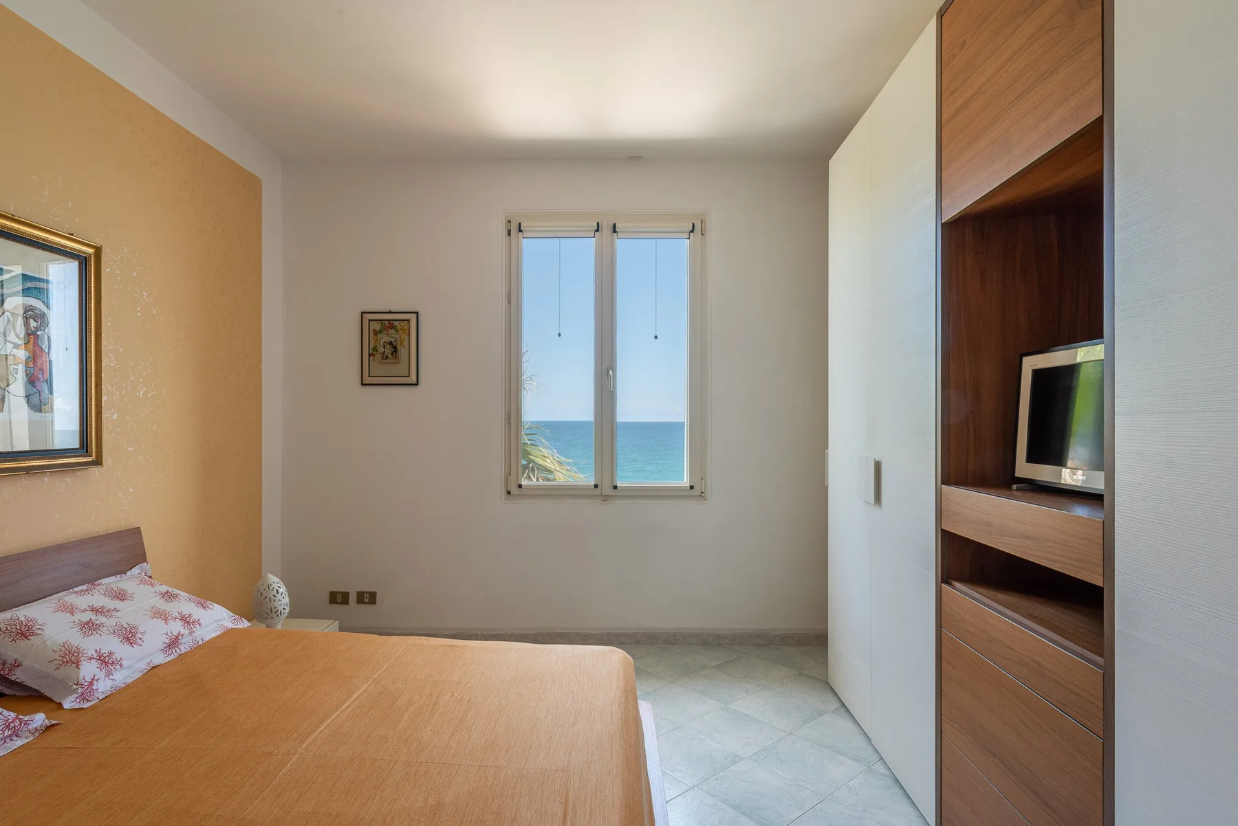 Un dormitorio con una cama, una ventana con vista al mar y estanterías empotradas.