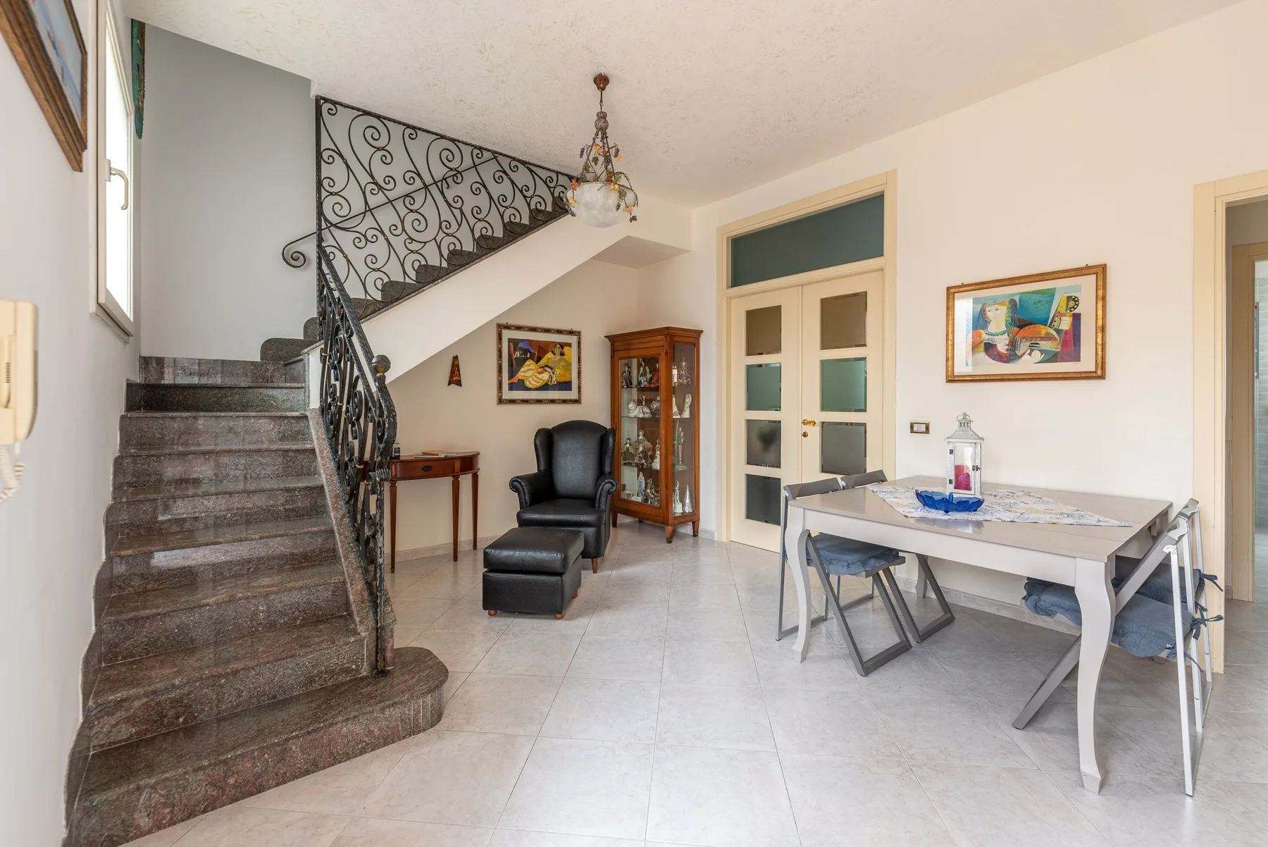 Un comedor junto a una escalera, con una mesa y sillas.