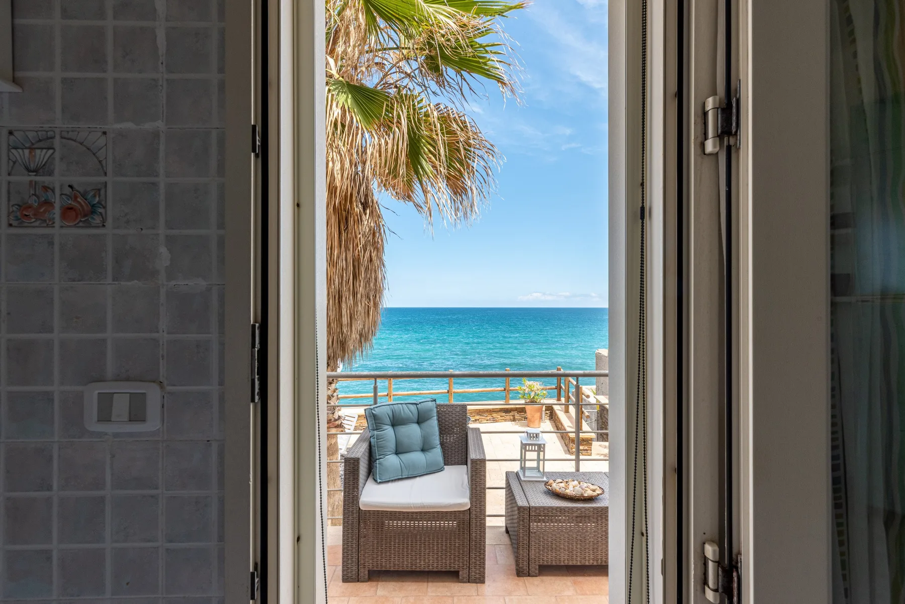 Un baño alicatado da a un balcón con vistas al mar.