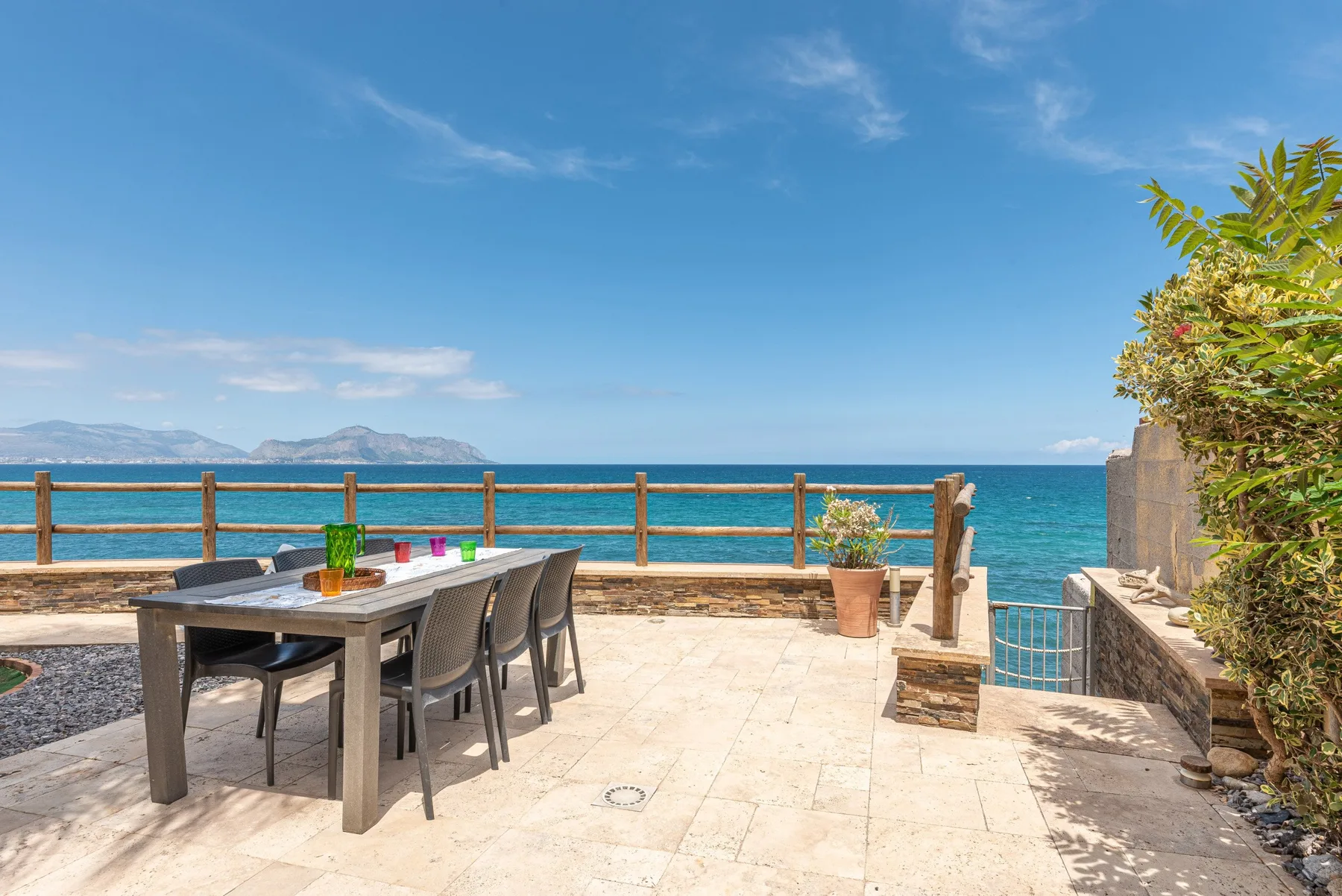 Un patio junto al mar tiene una mesa de comedor y sillas con vistas al agua.