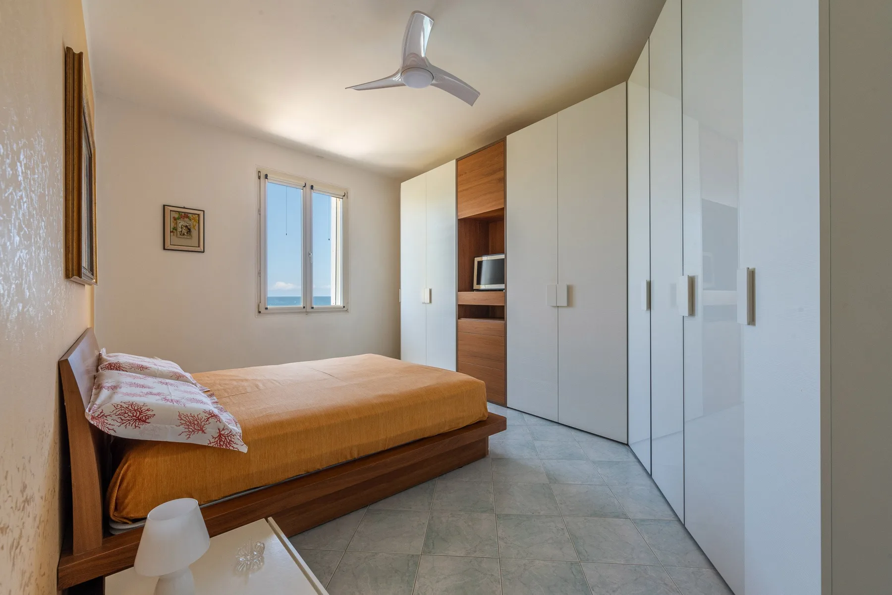 Un dormitorio con una cama junto a una pared de armarios blancos.