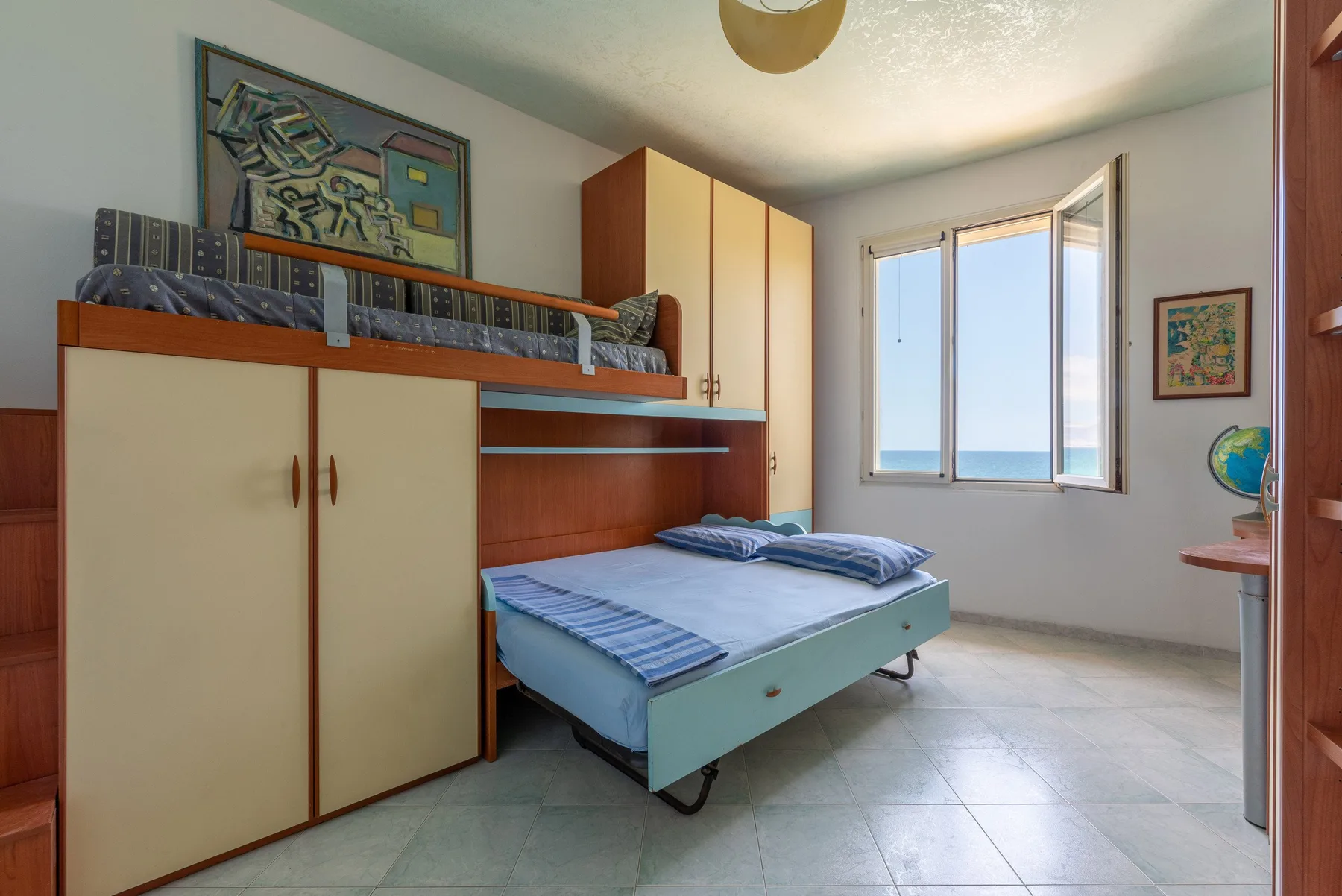 Un dormitorio con una cama bajo un espacio elevado para dormir y una ventana luminosa.