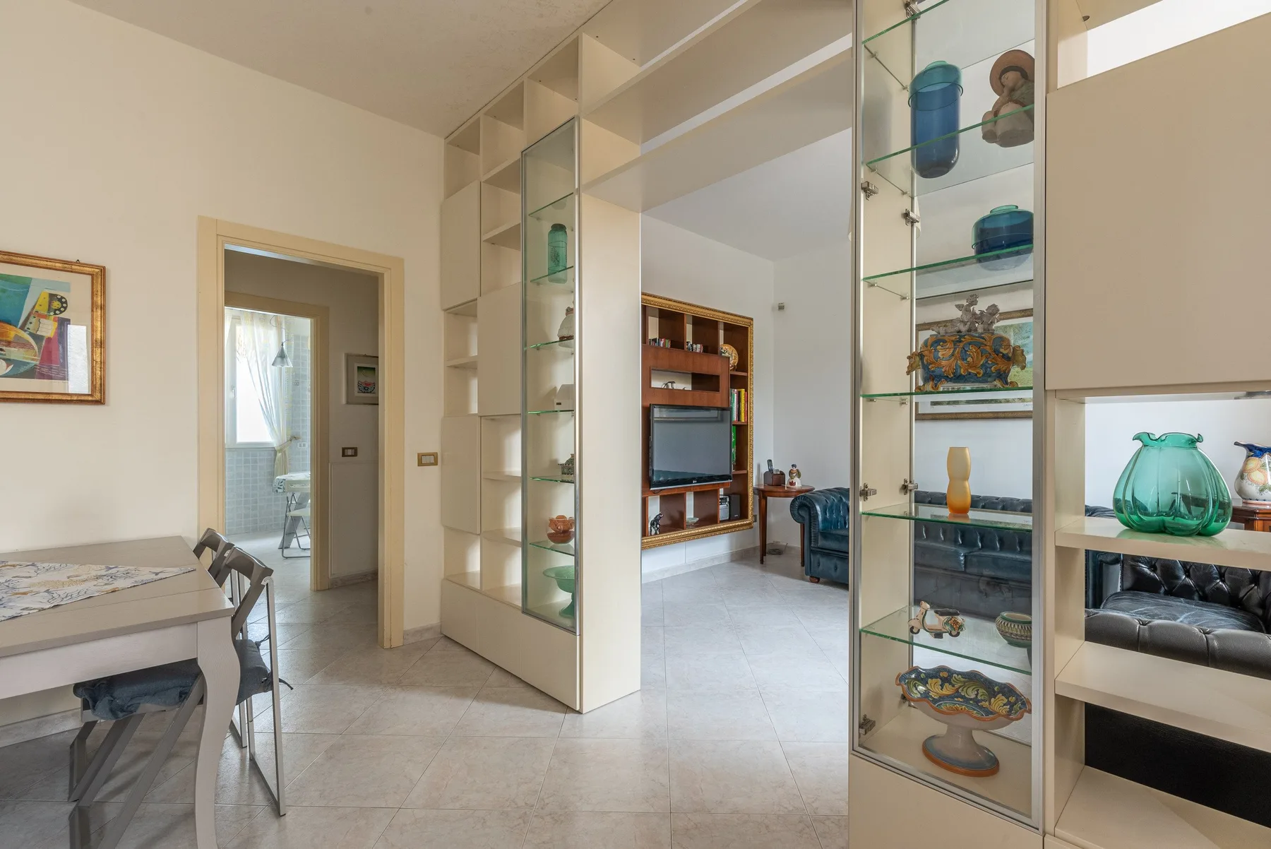 Una luminosa sala de estar y comedor con una vitrina de cristal y suelo de baldosas.