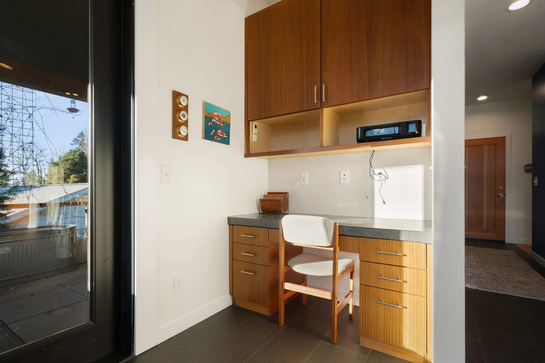 Una pequeña zona de cocina con armarios de madera, una encimera y una silla.