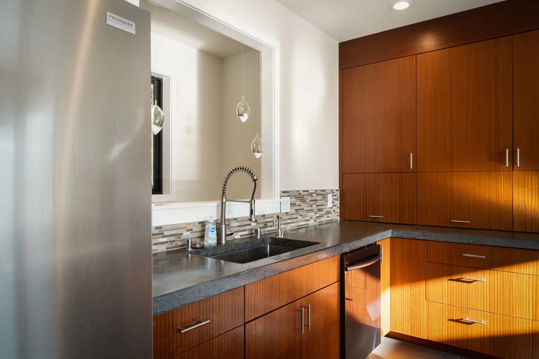 Una cocina moderna con encimera oscura, fregadero y gabinetes de madera.