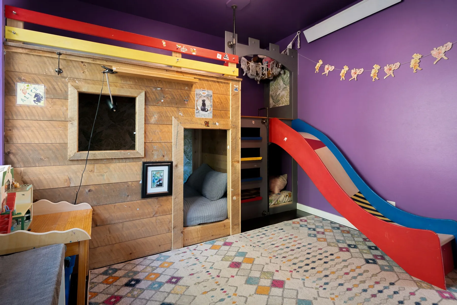 Una colorida sala de juegos infantil con una estructura de madera y un tobogán.