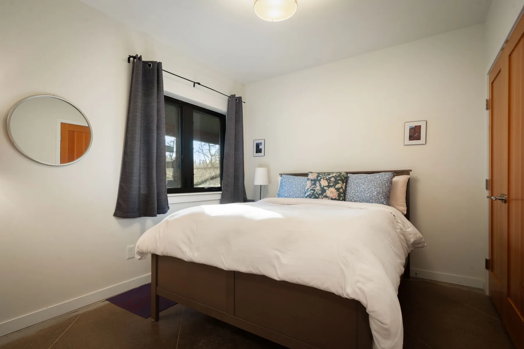 Un dormitorio con una cama bajo una ventana con cortinas oscuras.
