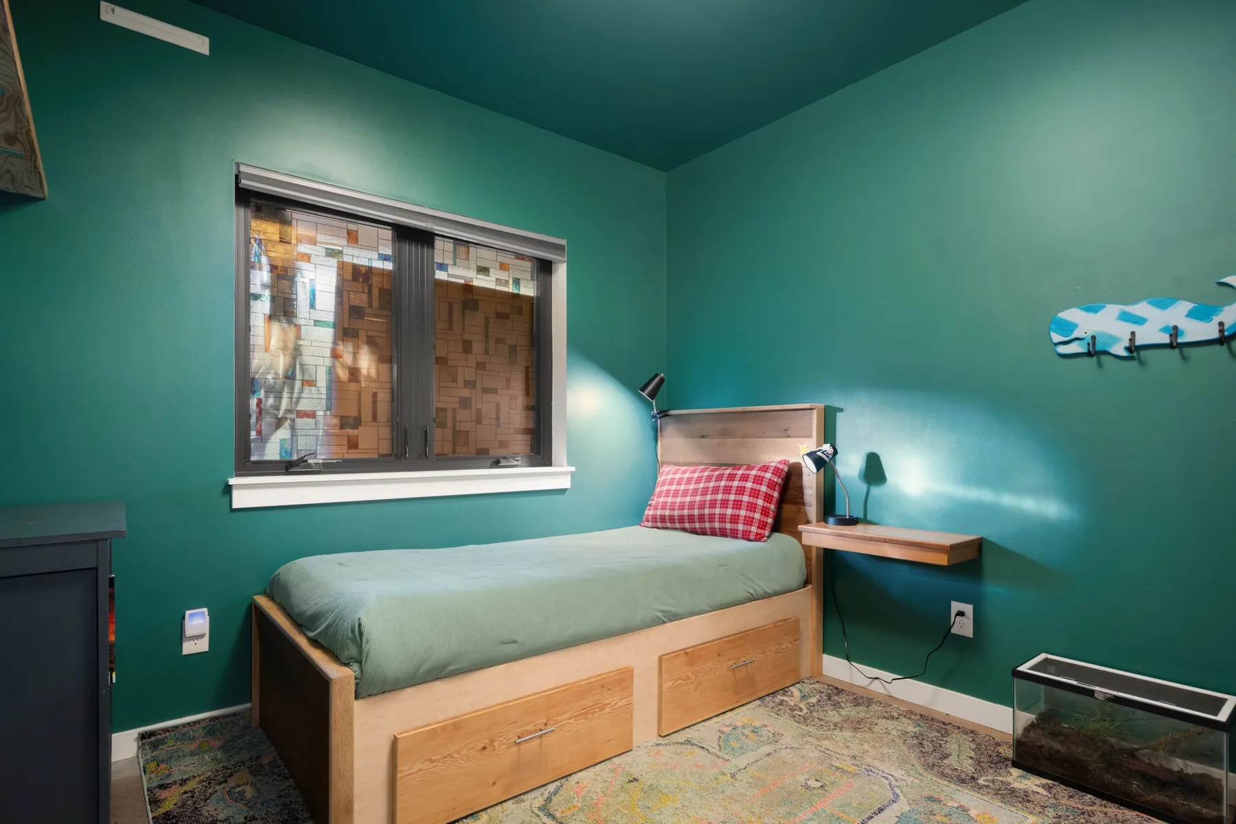 Un dormitorio con una cama individual, una mesita de noche y una ventana.