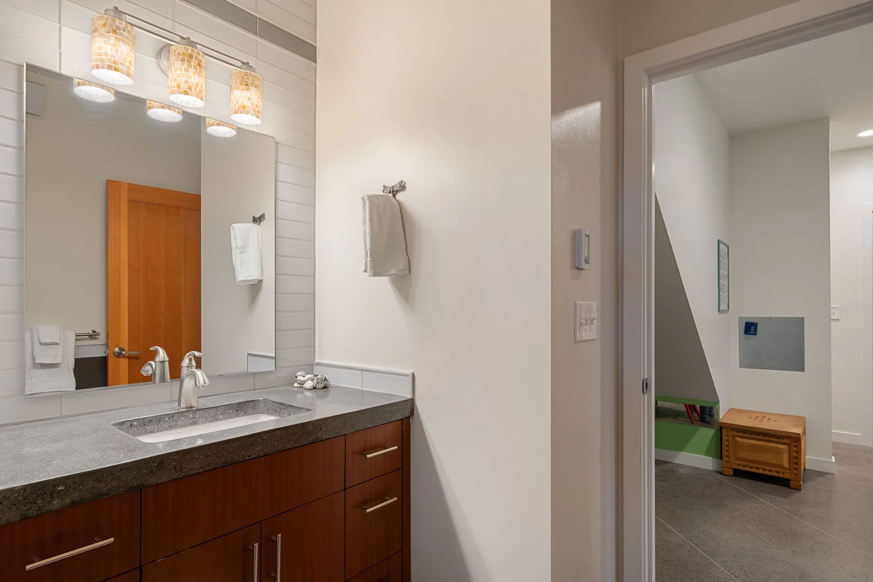 Un tocador de baño con un espejo amplio y una puerta hacia una habitación contigua.