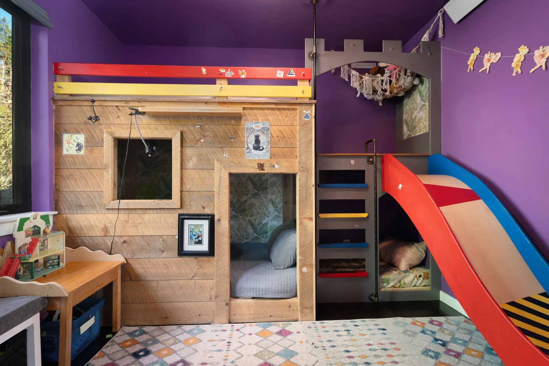Una colorida sala de juegos interior con una cama de madera y un tobogán.
