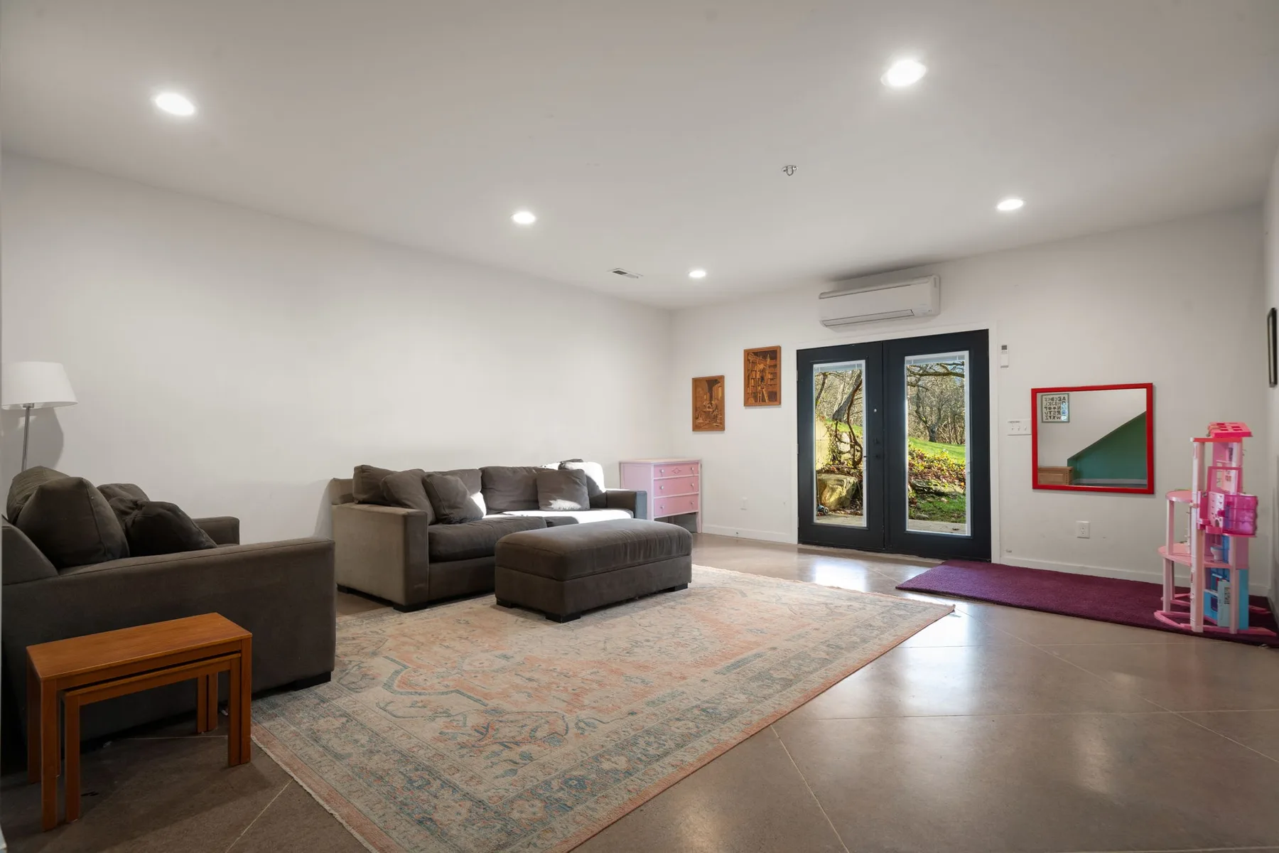 Una sala luminosa con asientos alrededor de una gran alfombra estampada y puertas de vidrio.