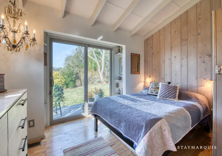 Un dormitorio con una cama junto a puertas de vidrio que dan a un jardín.