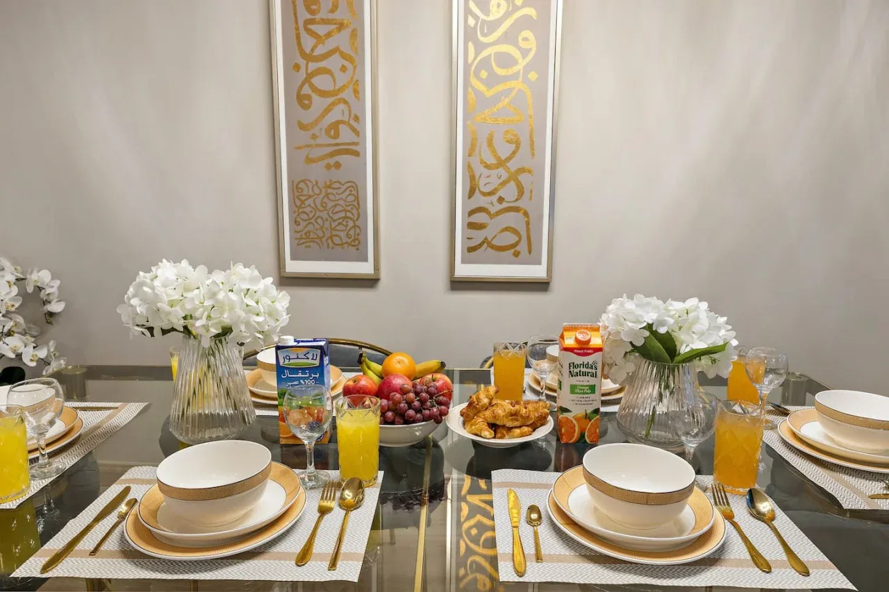 A dining table is set with plates, glasses, fruit, and white flowers.
