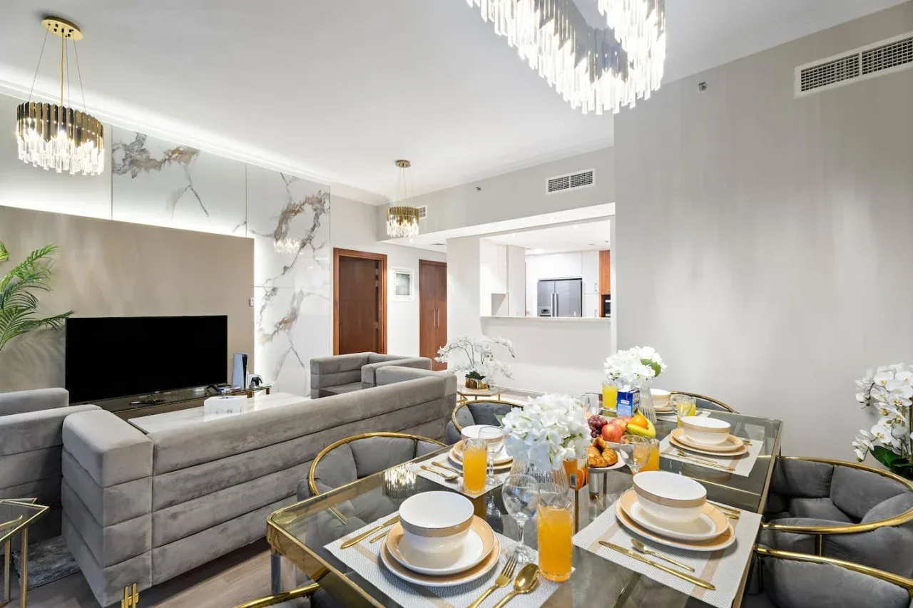 A bright living and dining area features gray seating and a set dining table.