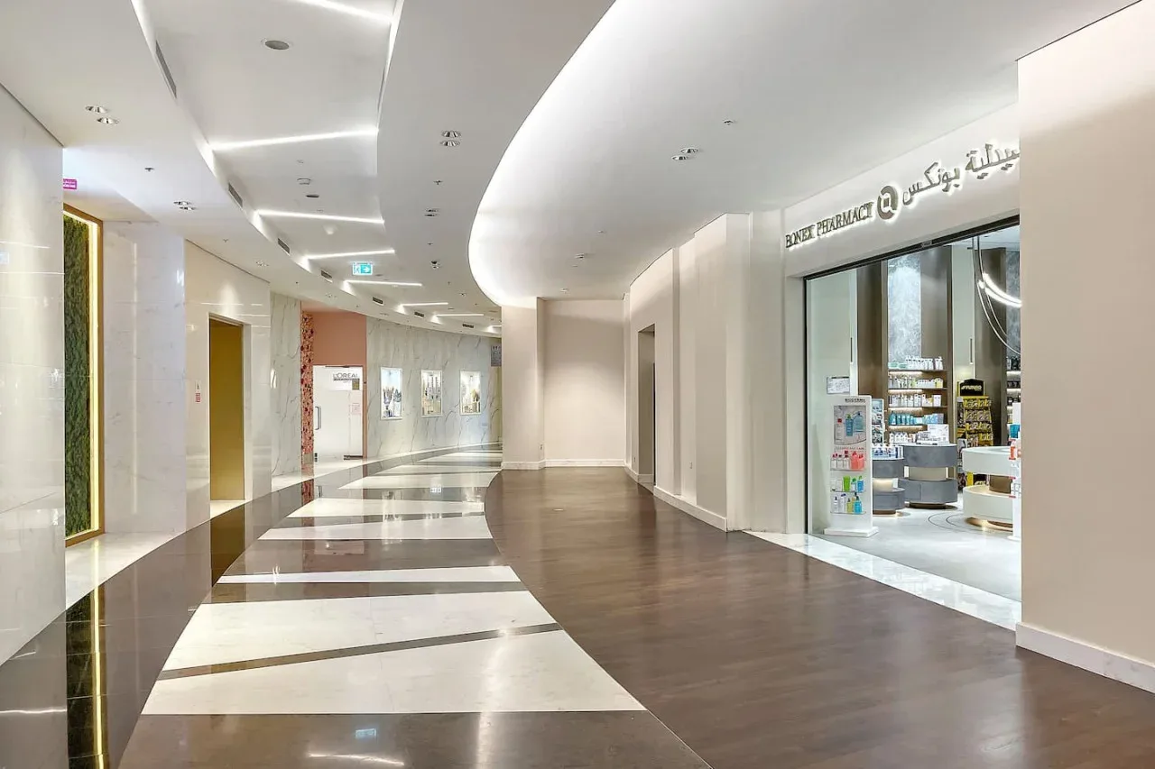 A bright indoor corridor with a curved ceiling and storefronts.
