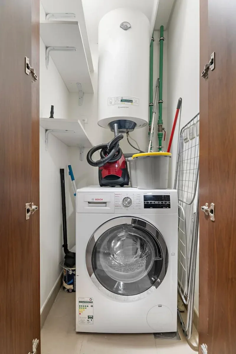 A laundry area with a front-loading washing machine and a water heater above it.