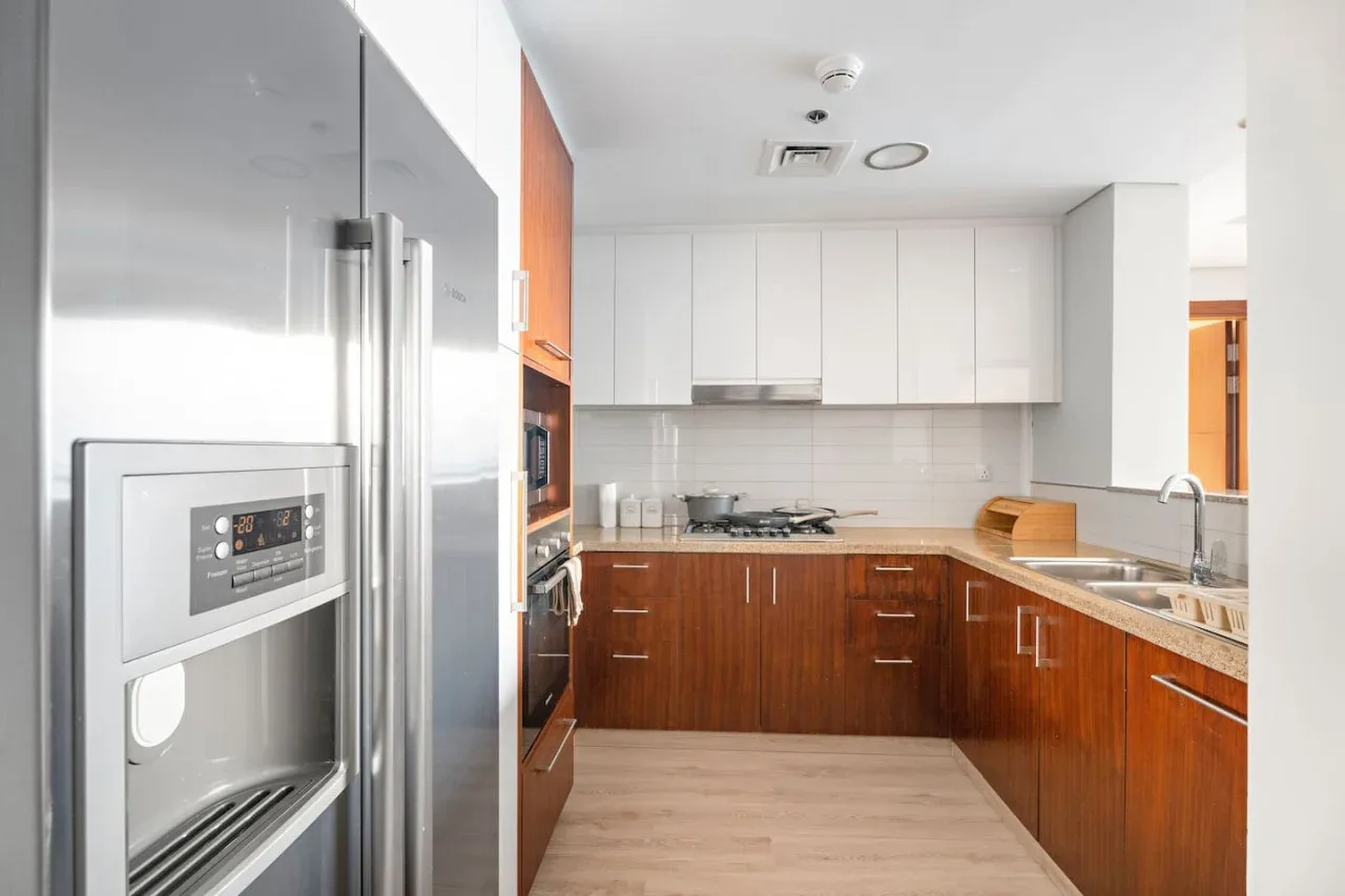 A modern kitchen with wood cabinets, white cupboards, and stainless steel appliances.