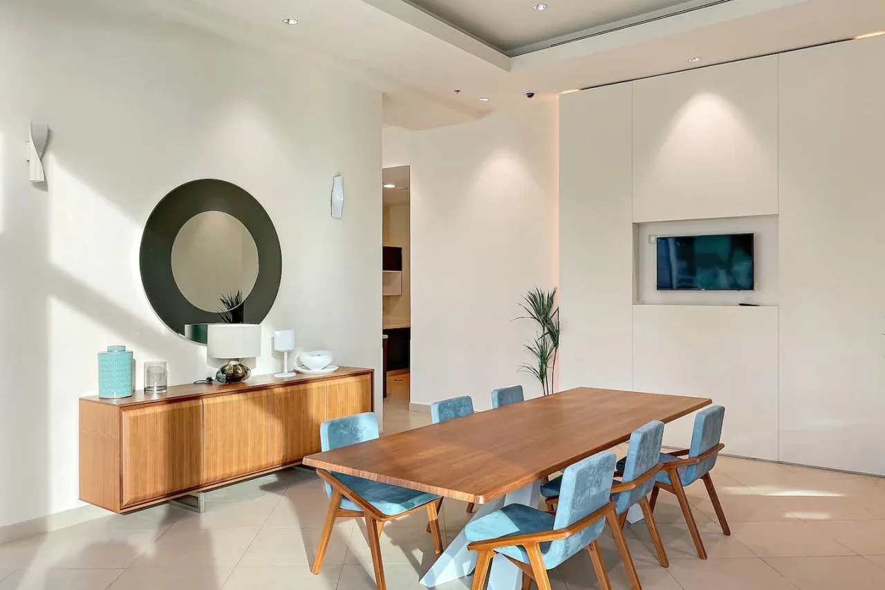 A dining area with a wooden table and blue seating beside a sideboard.