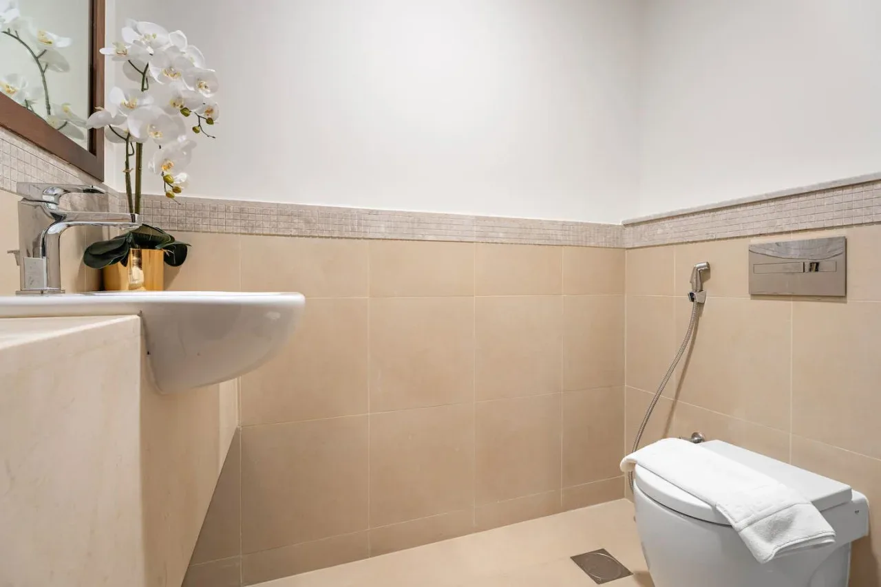 A bathroom with a sink, toilet, and white flowers.