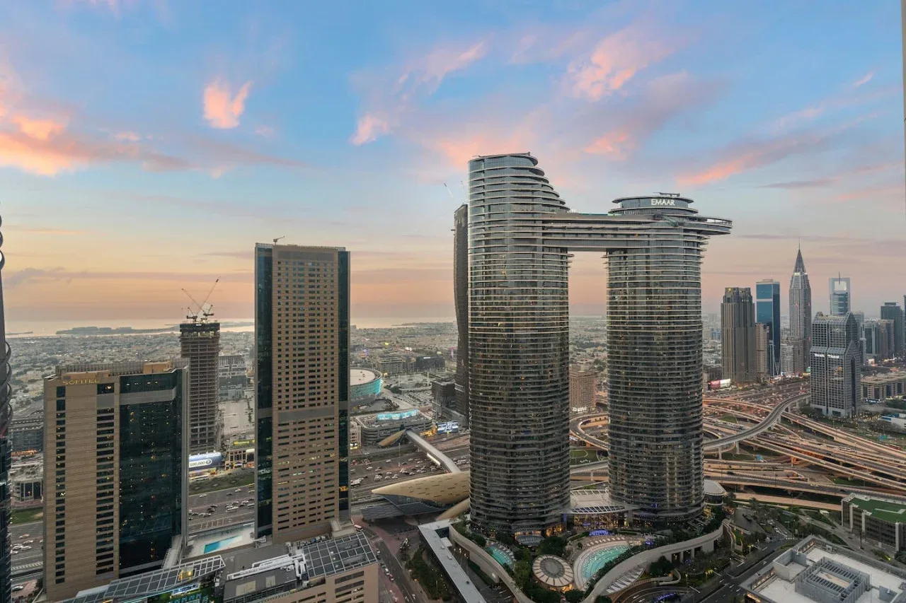City skyline with tall high-rise buildings and roads beneath a colorful evening sky.