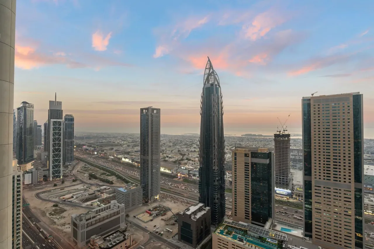 A city skyline at sunset, with tall buildings and roads in the foreground.