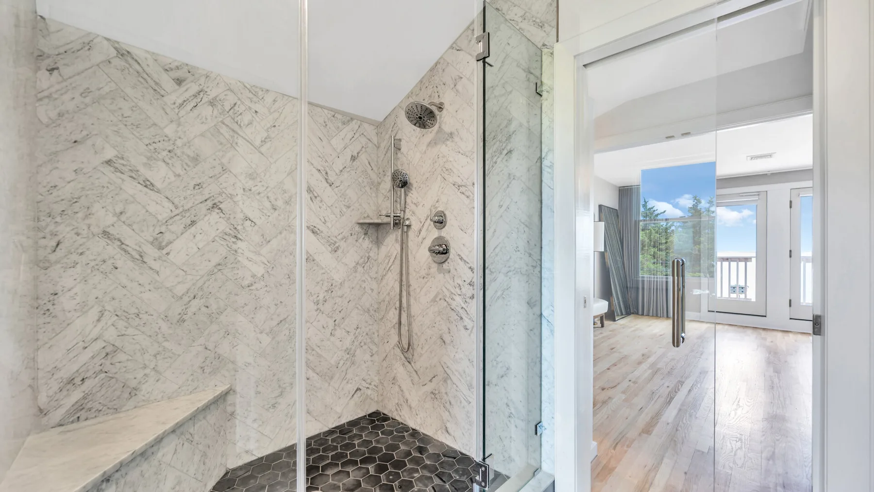 Una ducha con azulejos da a una estancia luminosa con ventanales.