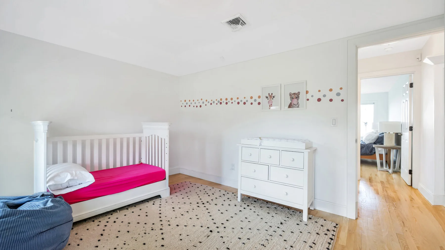 Un dormitorio luminoso con una cama blanca y una cómoda.