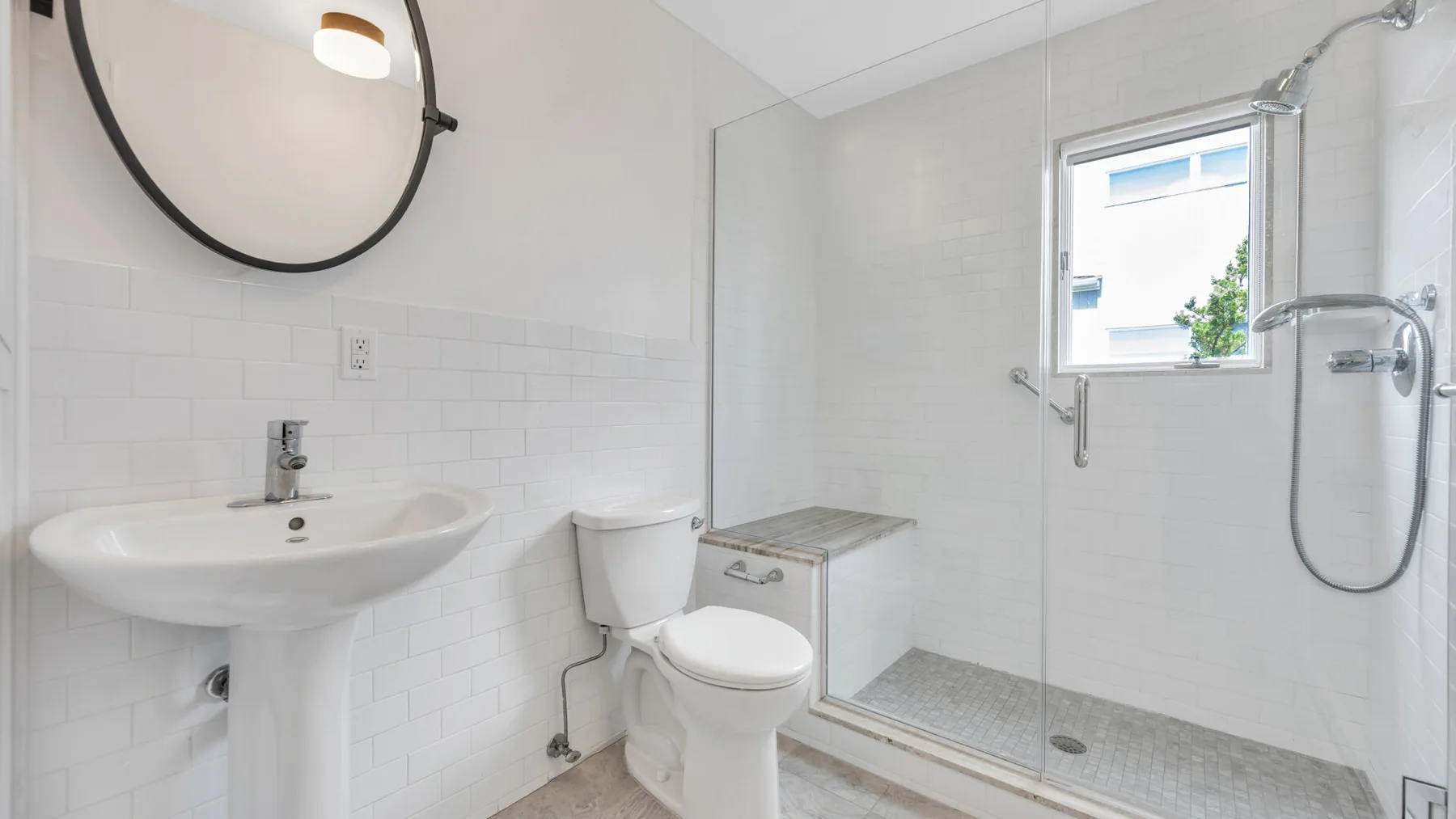 Un baño luminoso con lavabo, inodoro y ducha de vidrio.