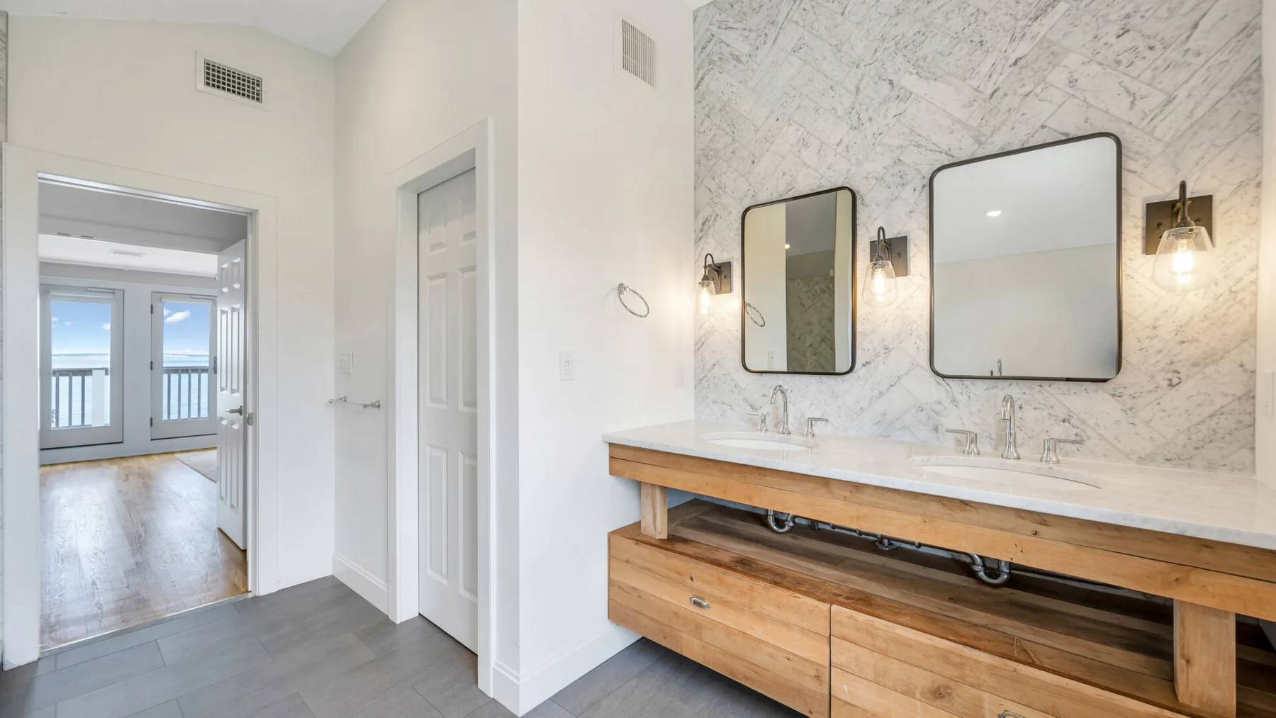 Un tocador de baño con una larga encimera de madera y dos espejos.