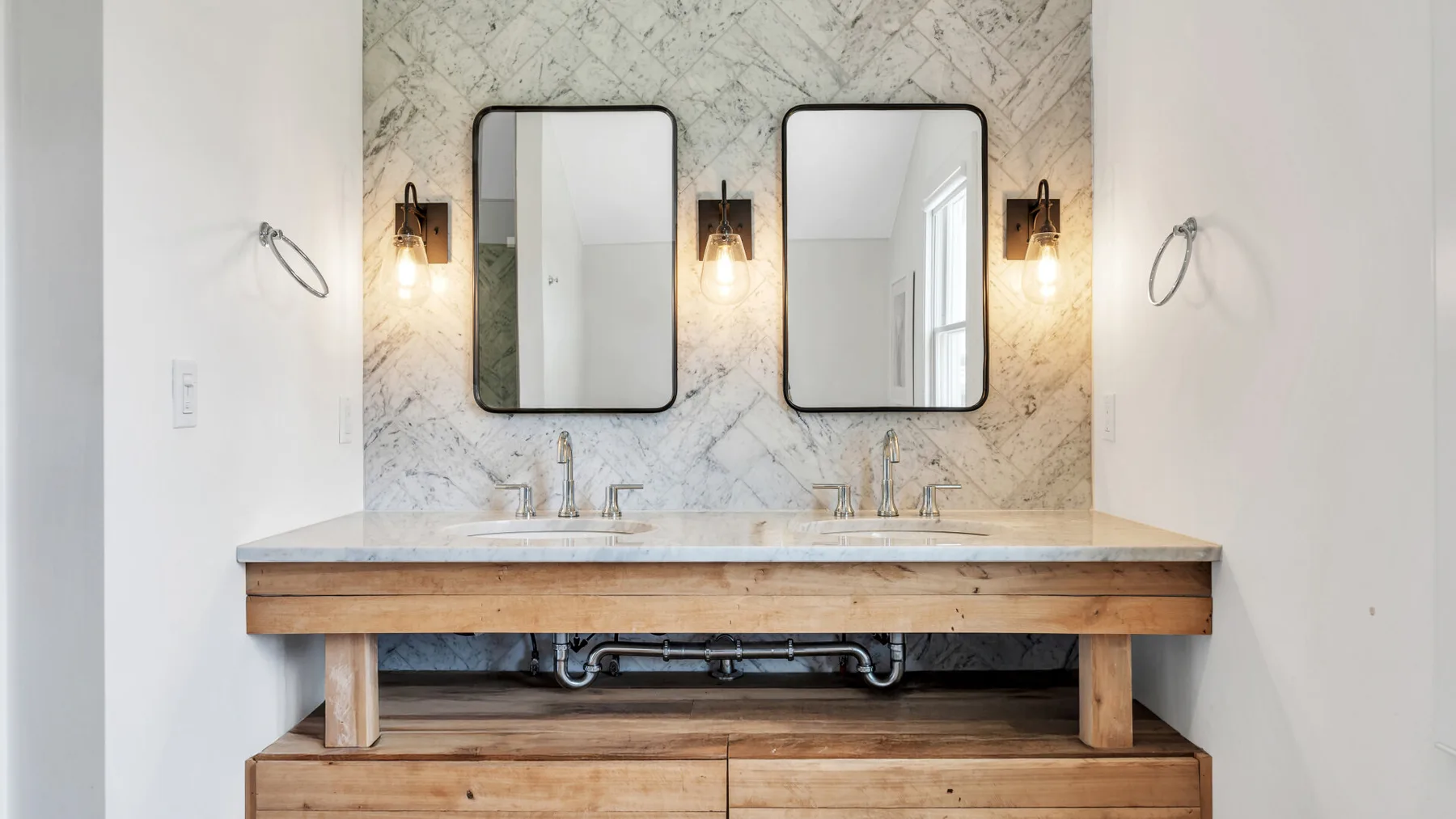 Un tocador de baño con dos espejos y luces en la pared.