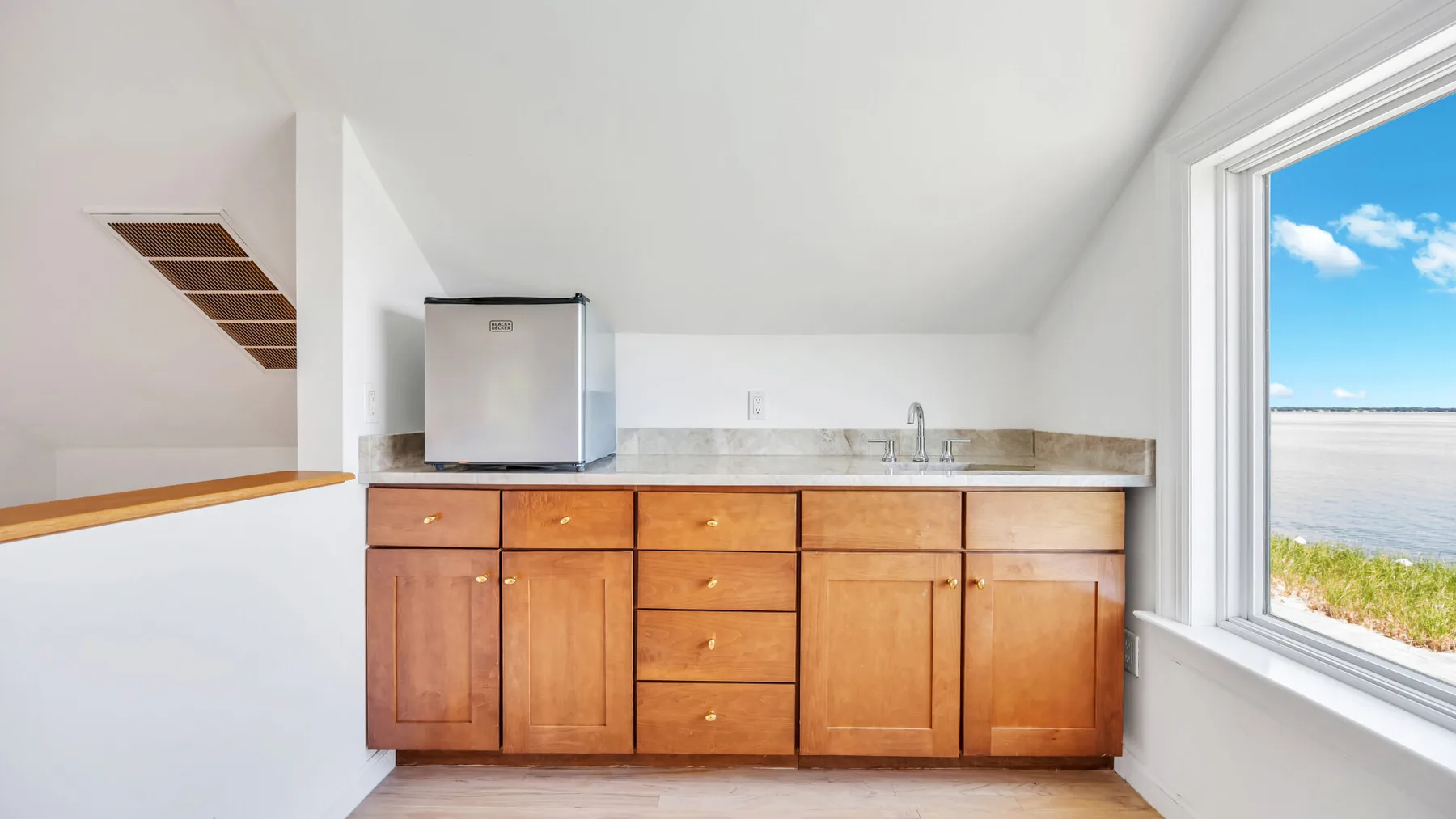 Una cocina compacta con gabinetes de madera y un fregadero junto a una ventana grande.