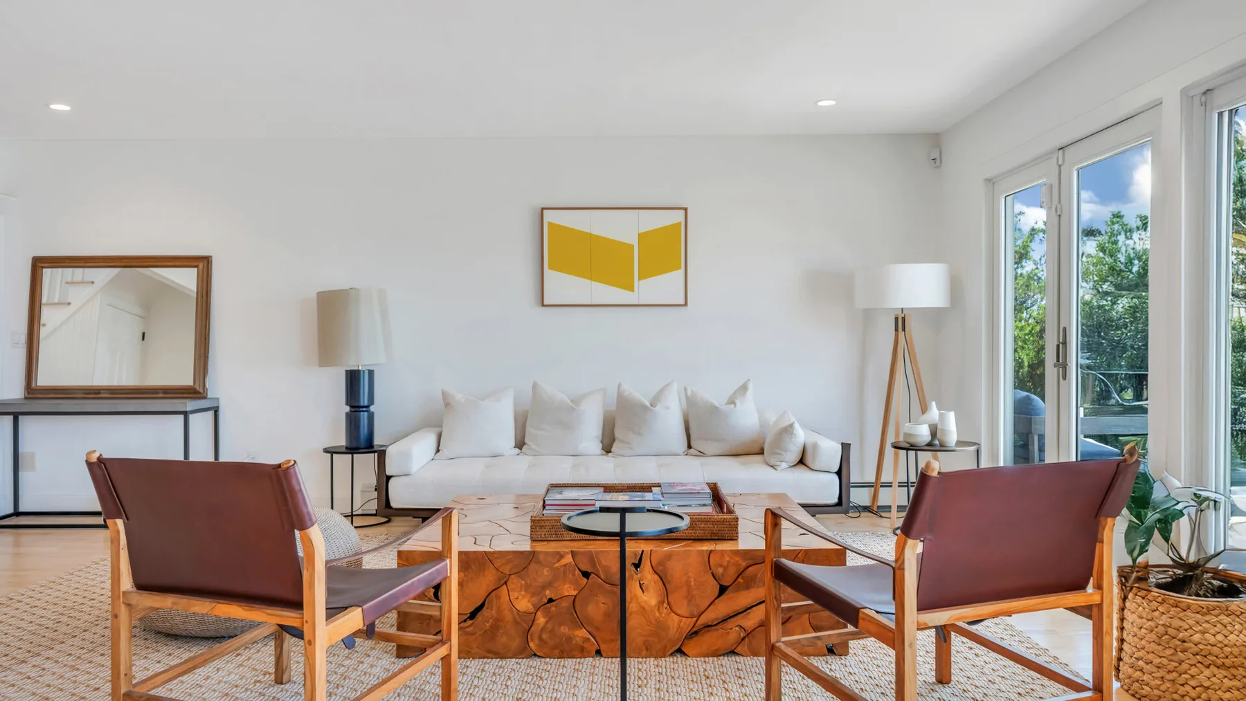 Una sala luminosa con asientos alrededor de una mesa baja y ventanas grandes.