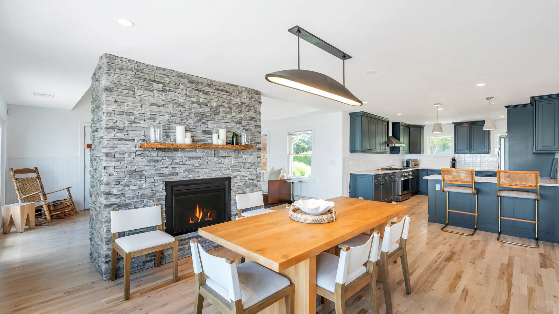 Un comedor de planta abierta con cocina cuenta con una mesa de madera y una chimenea de piedra.