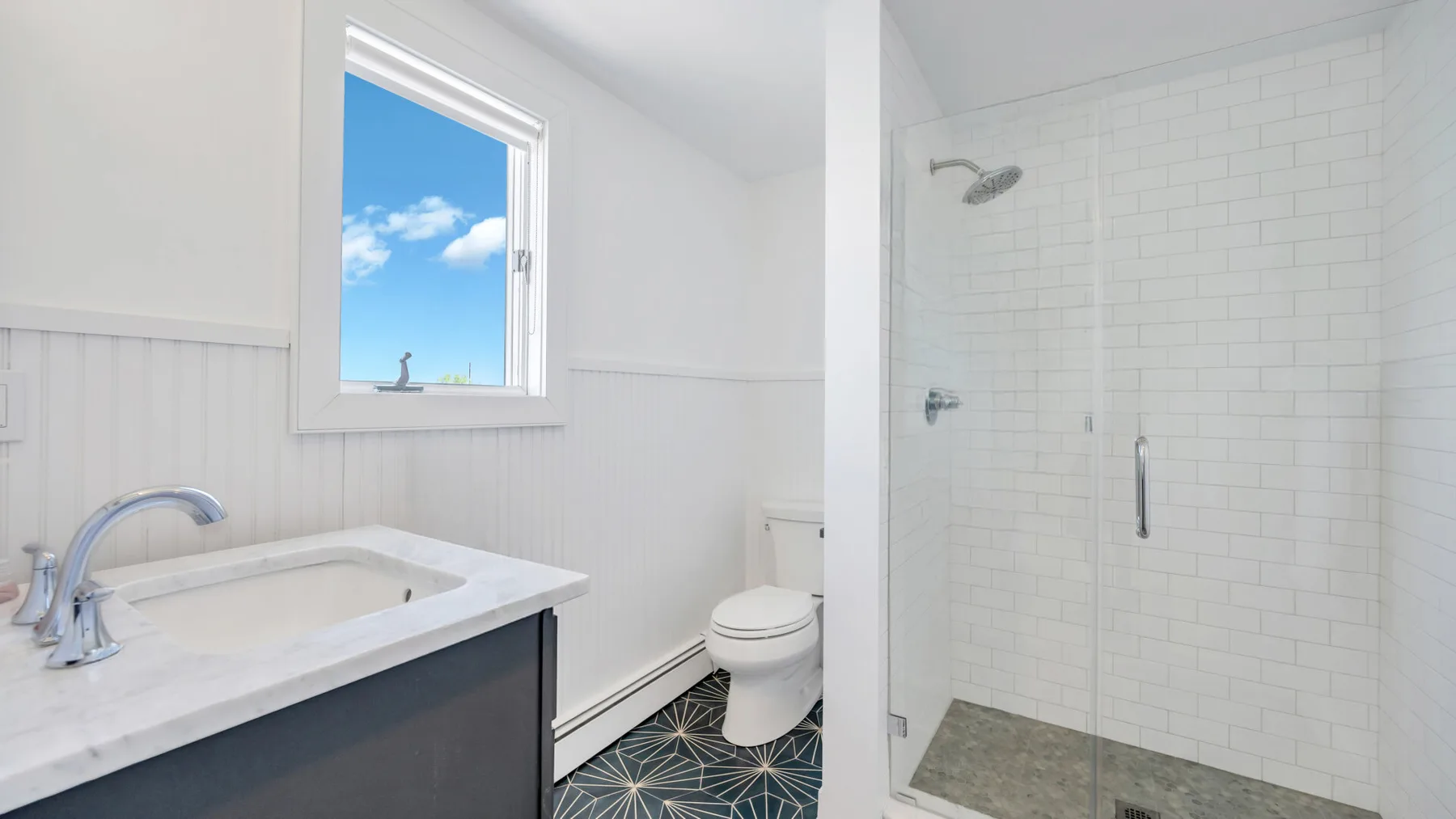 Un baño luminoso con lavabo, inodoro y ducha con mampara de vidrio.