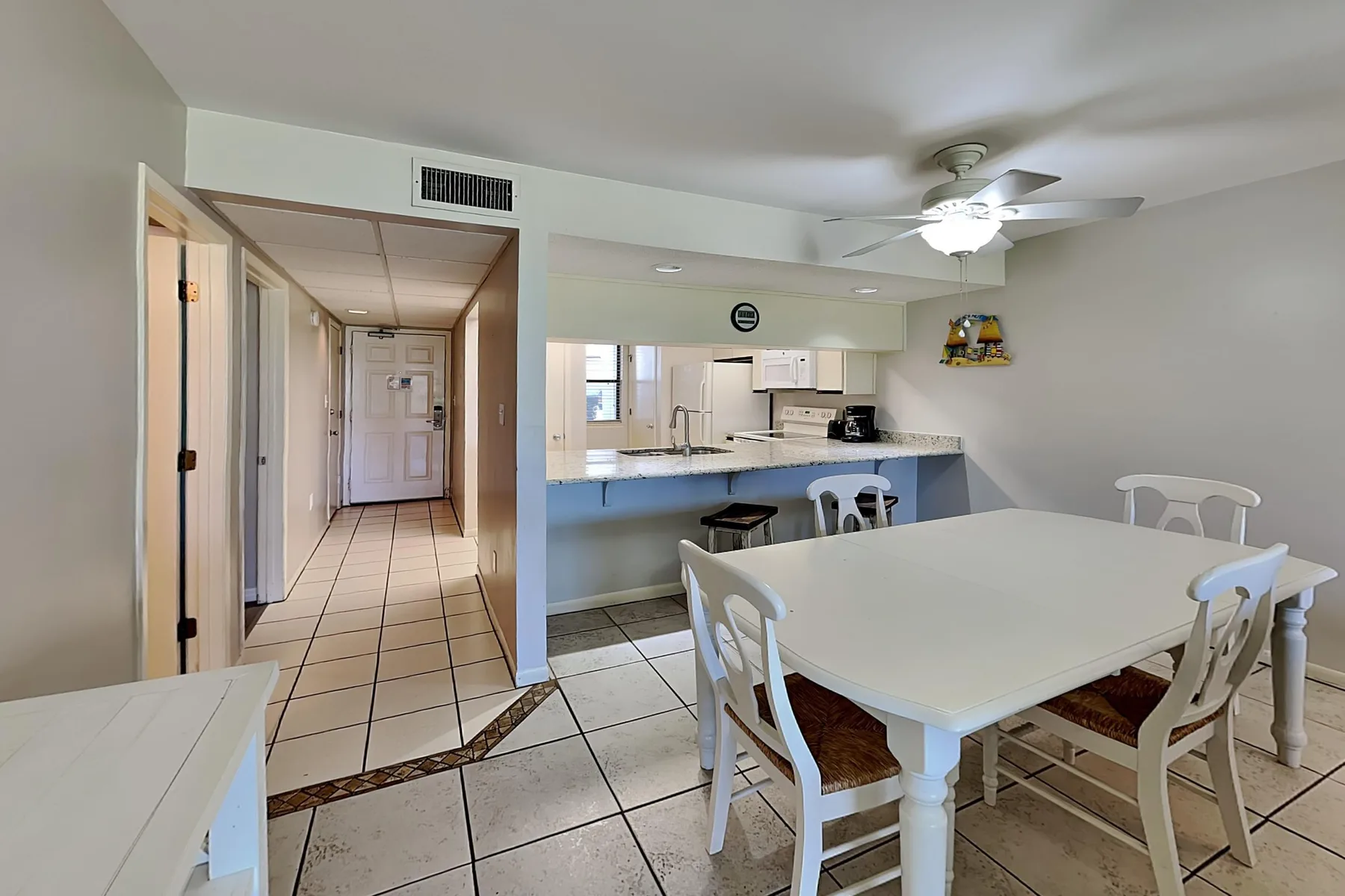 Un comedor con una mesa blanca y sillas junto a una barra de cocina.
