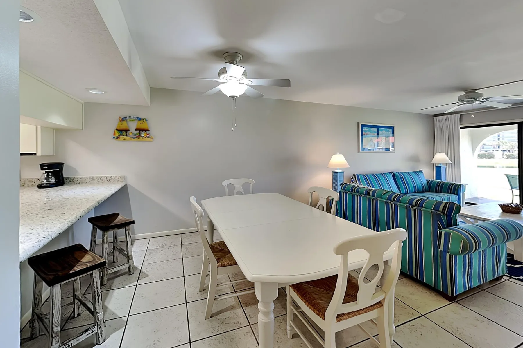 A dining area with a long table beside a blue-striped seating area.