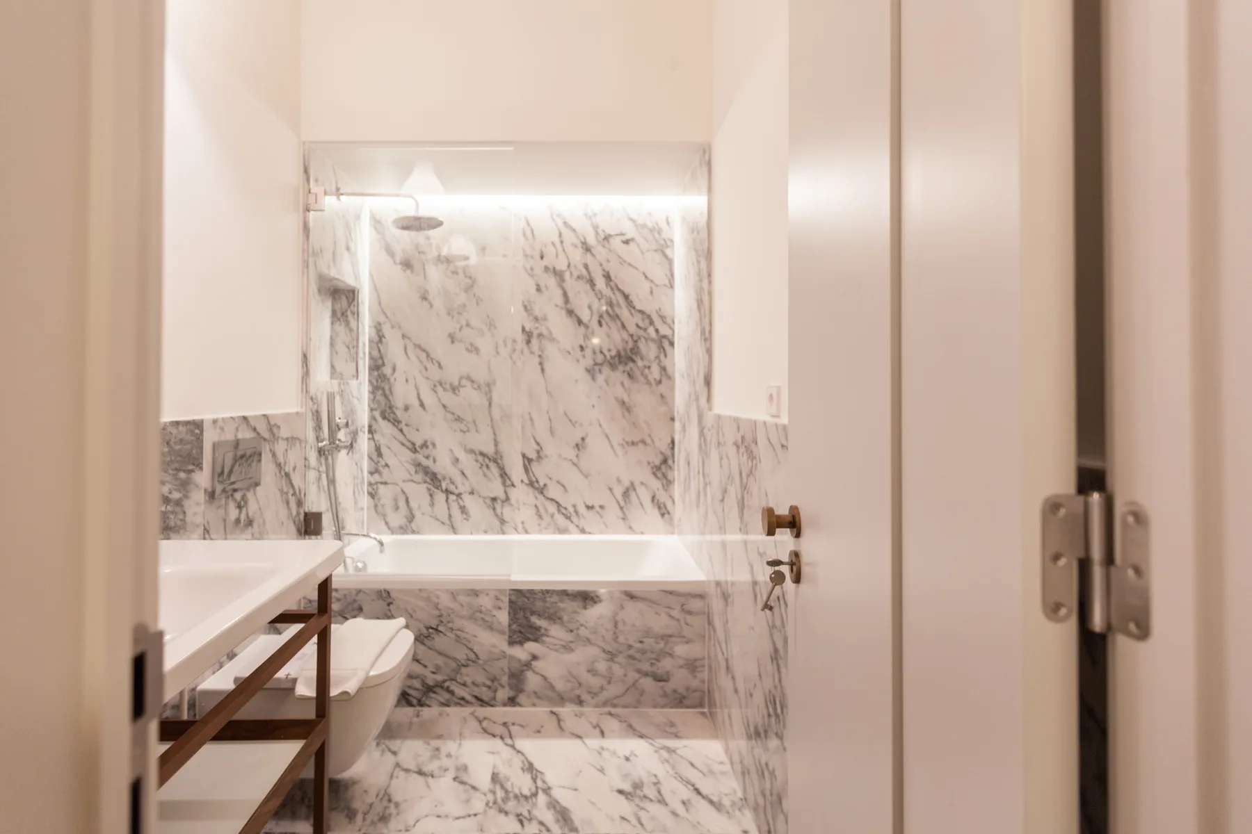 A bathroom with a bathtub and marble-patterned wall surfaces.