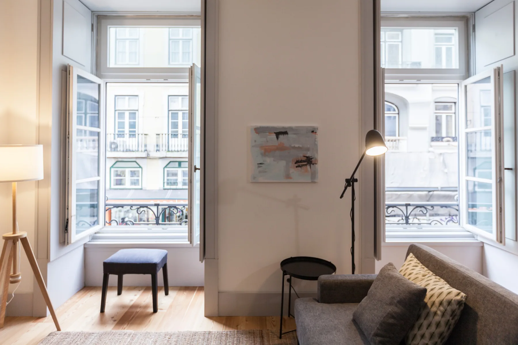 Living room with open windows, a sofa, and a floor lamp.