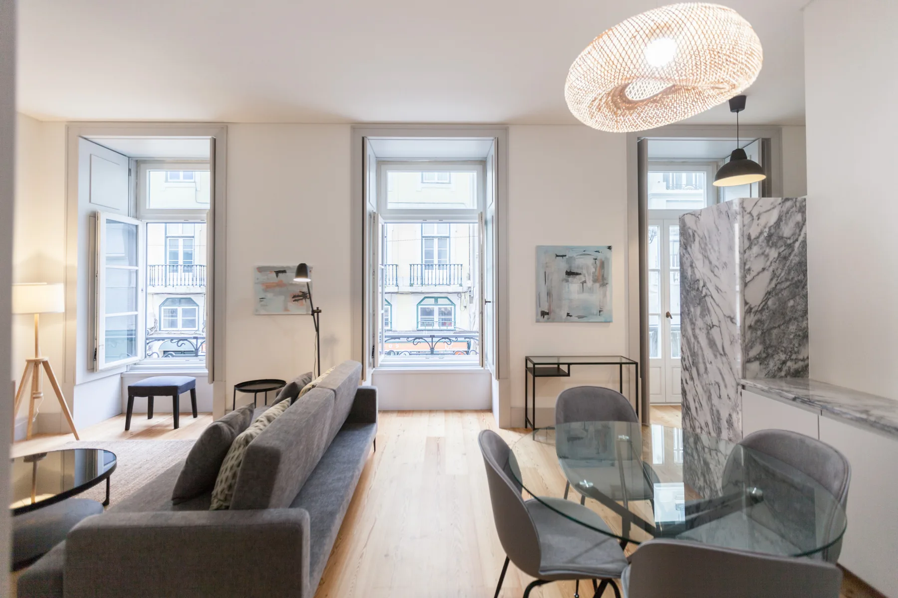 A bright living and dining area with large windows and a glass table.