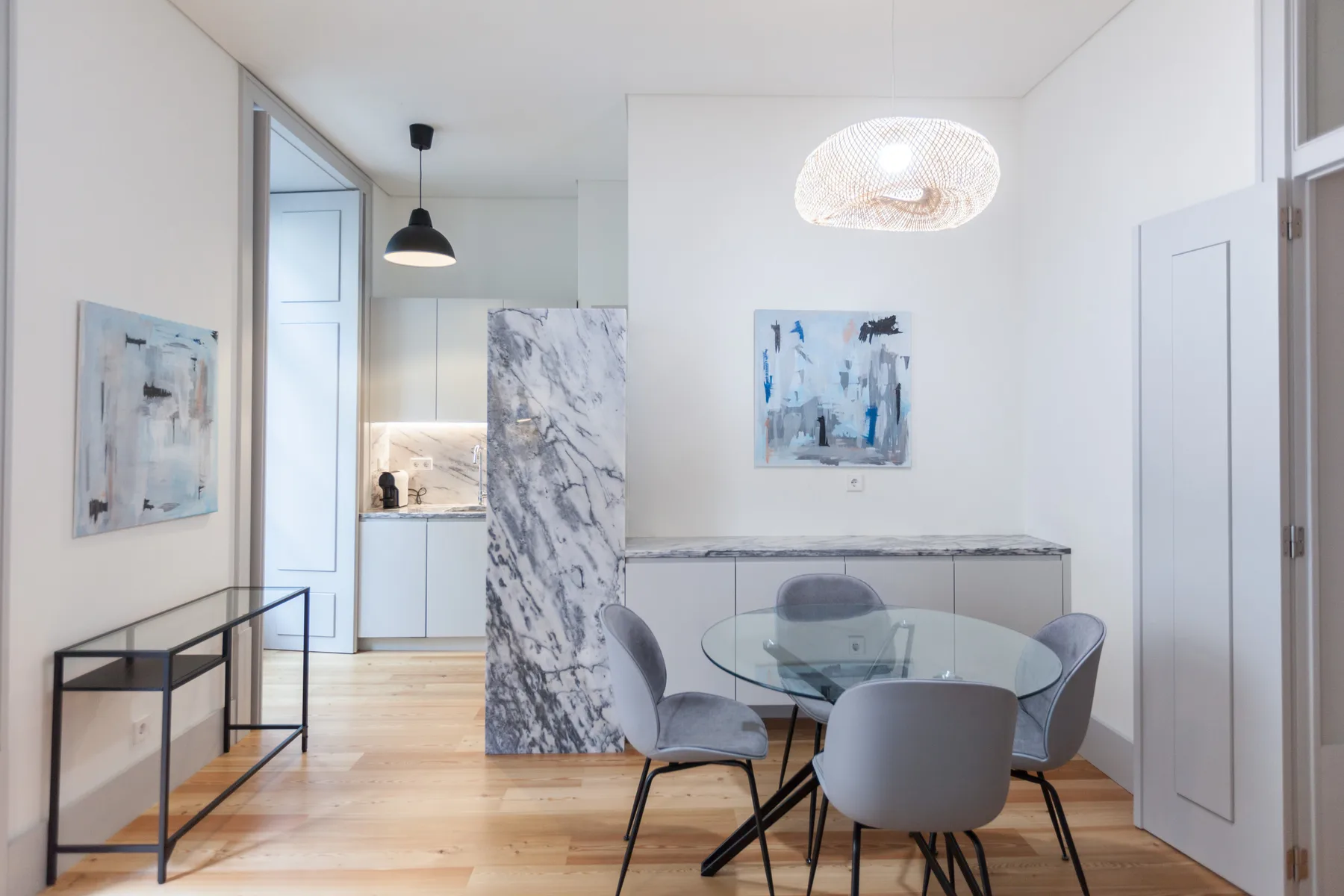 A bright dining area with a glass table beside a compact kitchen.