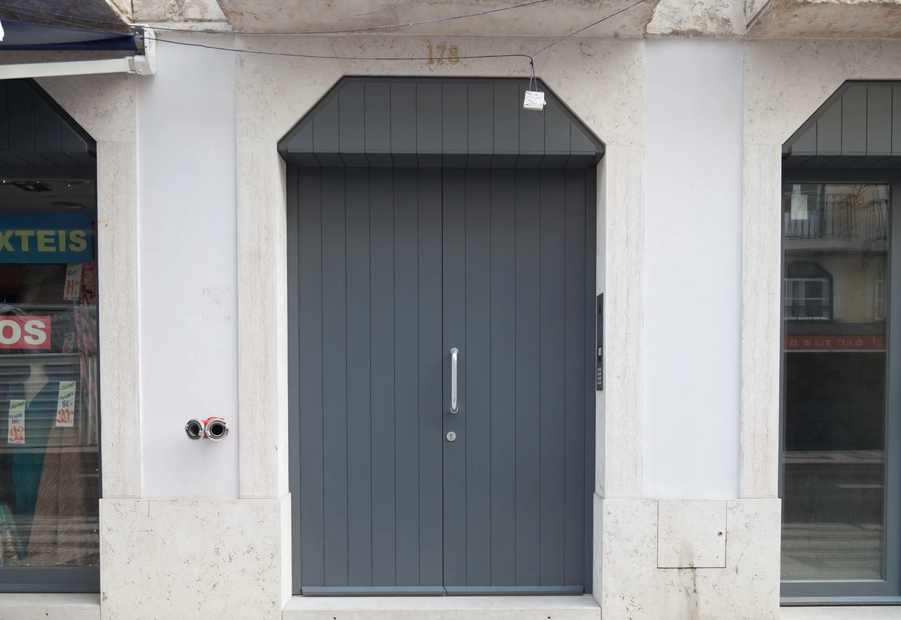A dark entrance door is set into a pale stone facade.