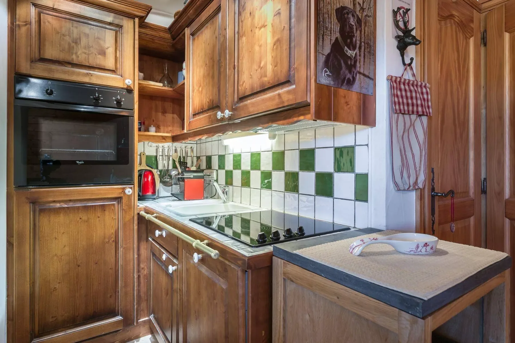 A wood-paneled kitchen with a tiled backsplash and a small central worktable.