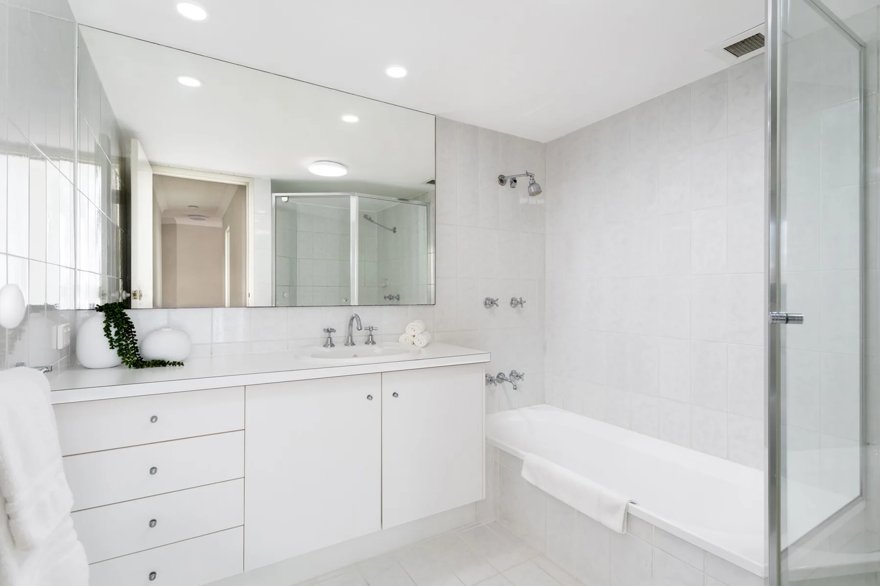 Baño luminoso con bañera, mampara de vidrio y un amplio lavabo.